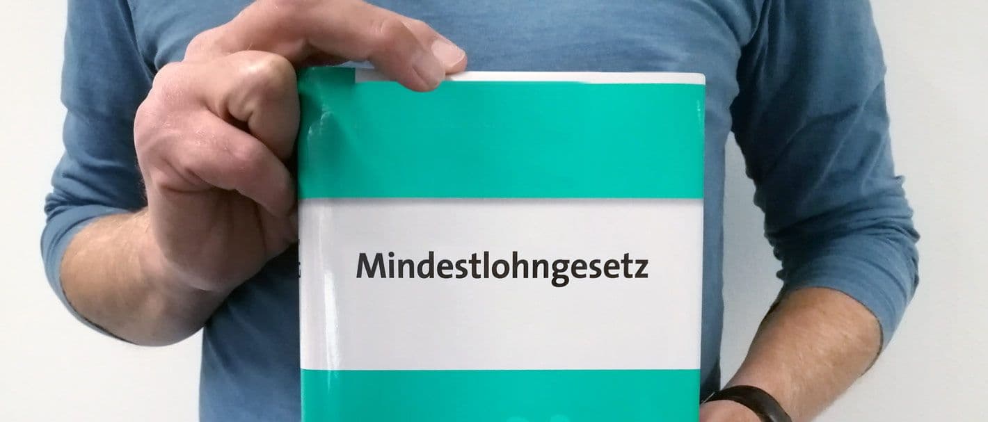 Mann hält Mindestlohngesetz in Händen.