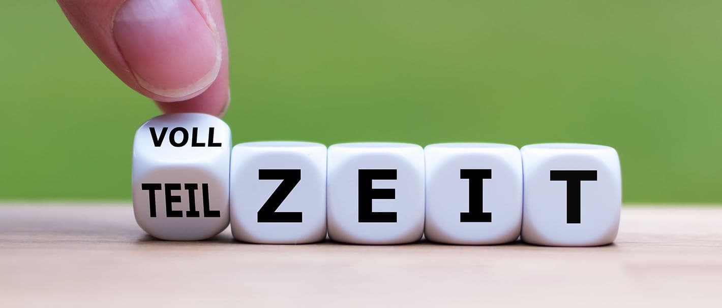 Eine Hand dreht den ersten Würfel einer Würfelreihe mit Buchstaben und ändert so das Wort "Vollzeit" in "Teilzeit" oder umgekehrt.