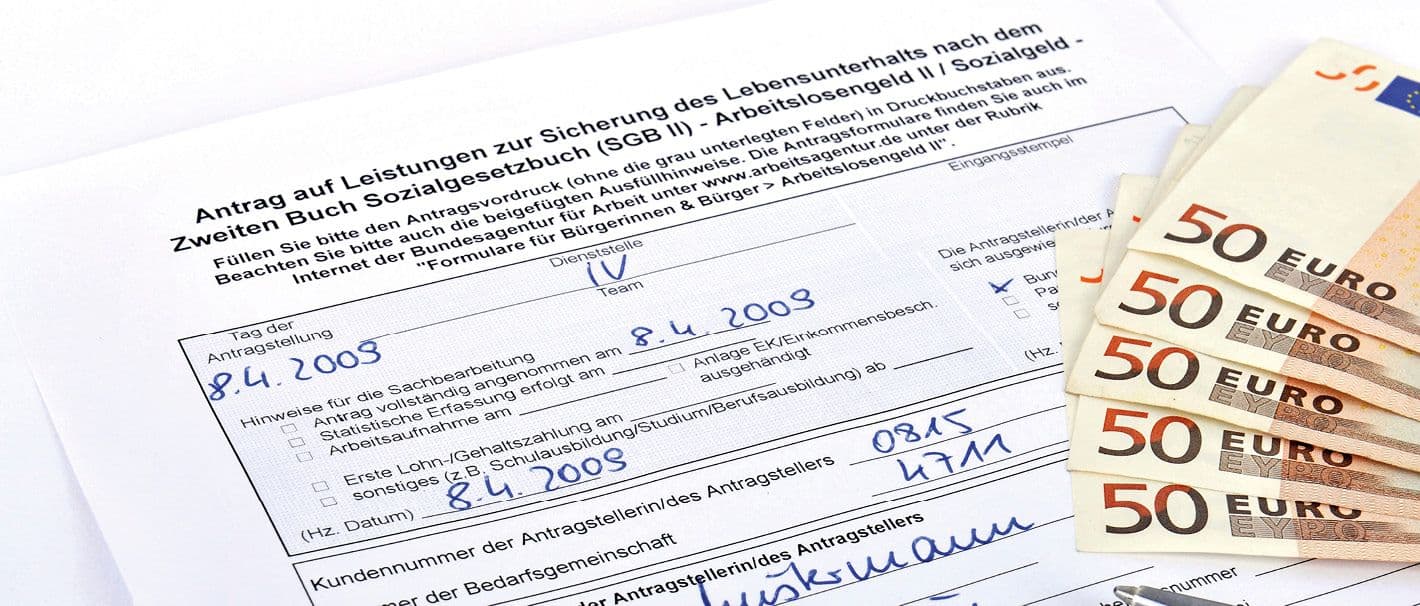 Ausschnitt eines Antrags auf Leistungen zur Sicherung des Lebensunterhalts nach dem SGB II undfünf Fünzog-Euro-Scheine