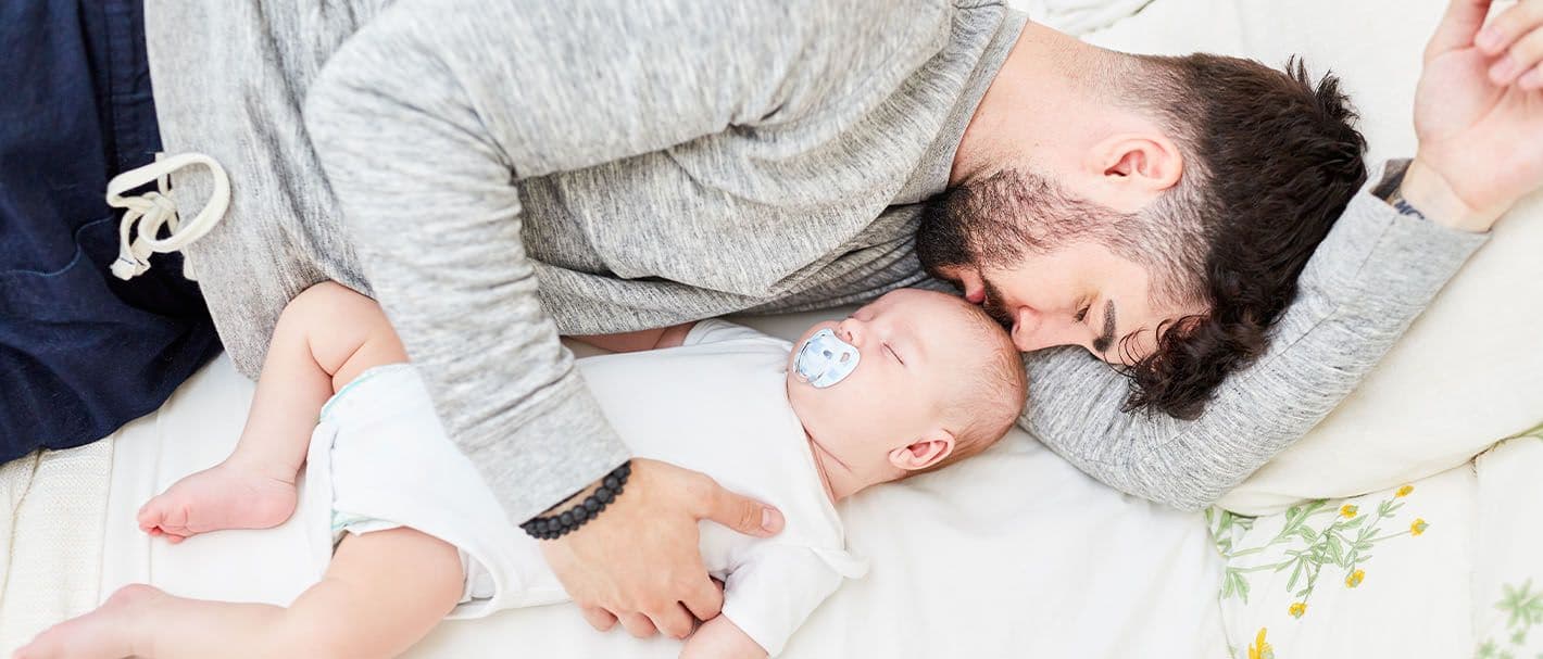 Vater kuschelt sich an sein schlafendes Baby