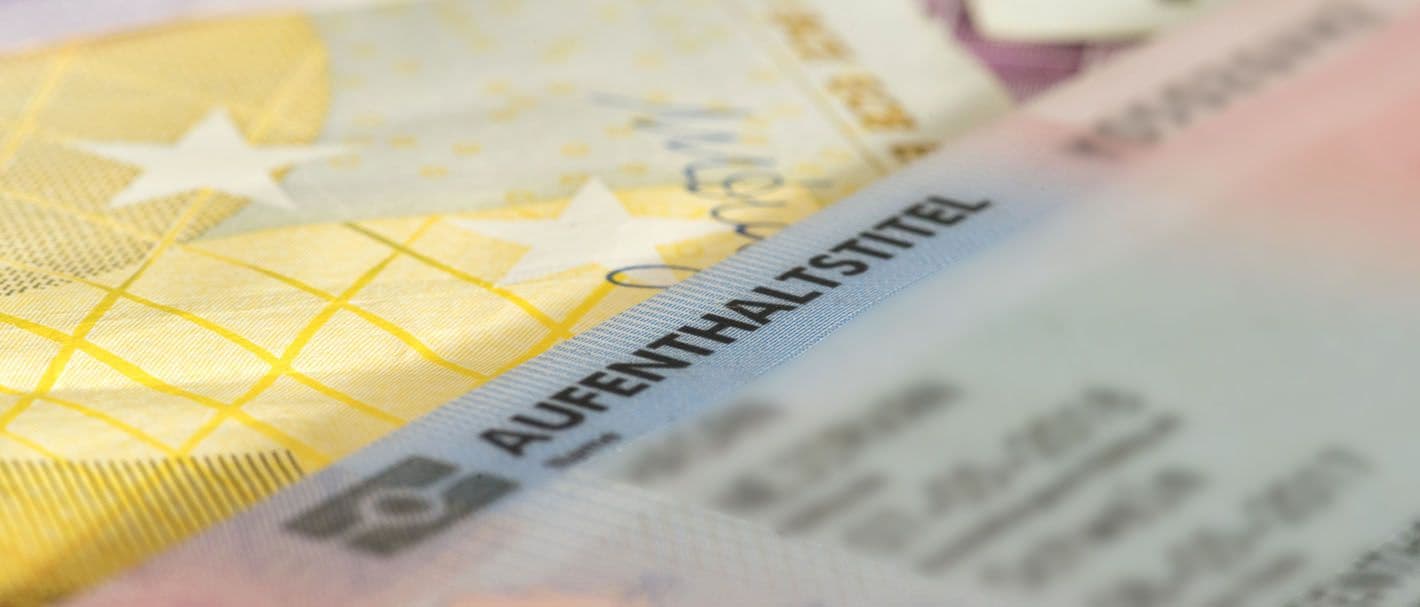 Nahaufnahme einer Aufenthaltserlaubnis für Deutschland, die auf Euro-Geldscheinen liegt.