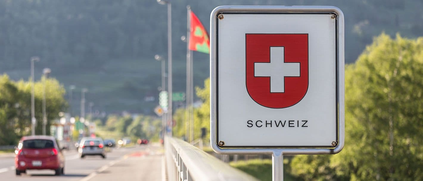 Autos fahren auf einer Straße über die Schweizer Grenze.