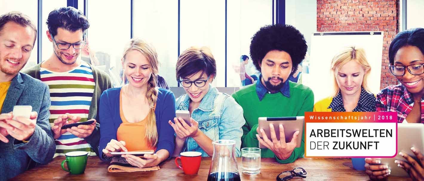 "Bunte Truppe" an jungen Leuten mit ihren Smartphones und Tablets sitzt um einen Tisch