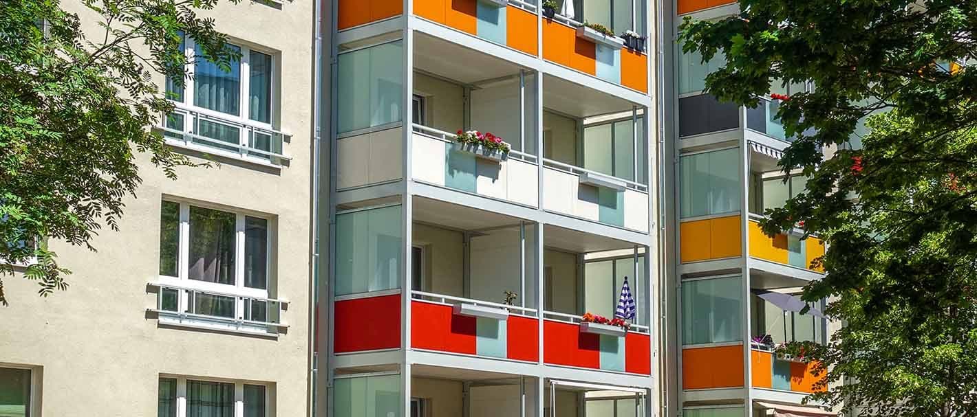 Fassade eines Mehrfamilienhauses mit verschiedenfarbigen Balkonen.