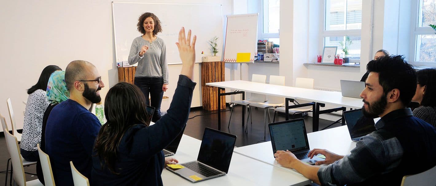 Person hebt den Arm für eine Wortmeldung in einem Kurs